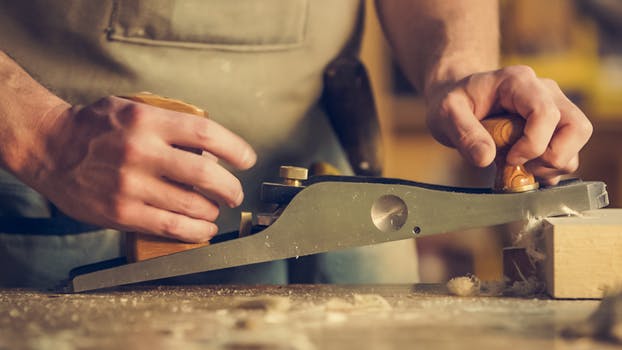Close up of a joinery workshop with a man slicing into wood.